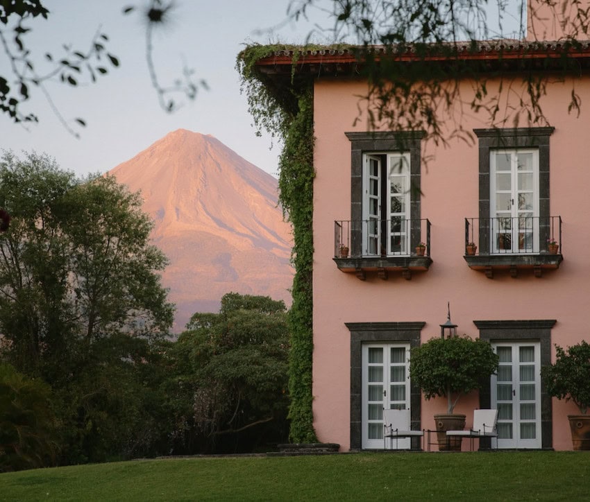 The pink exterior of the Hacienda San Antonio with a mountain in the background